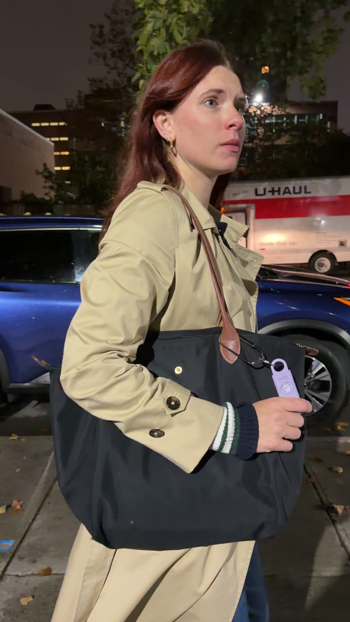 Woman in a trench coat with Sally clipped to her bag